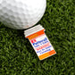 A golf ball on artificial grass sits beside Logie Joe's Golf RX Putterall—a novelty pin shaped like a prescription bottle labeled “Take 3 Daily; WARNING May Be Habit Forming”—and a magnetic ball marker for your next putt.