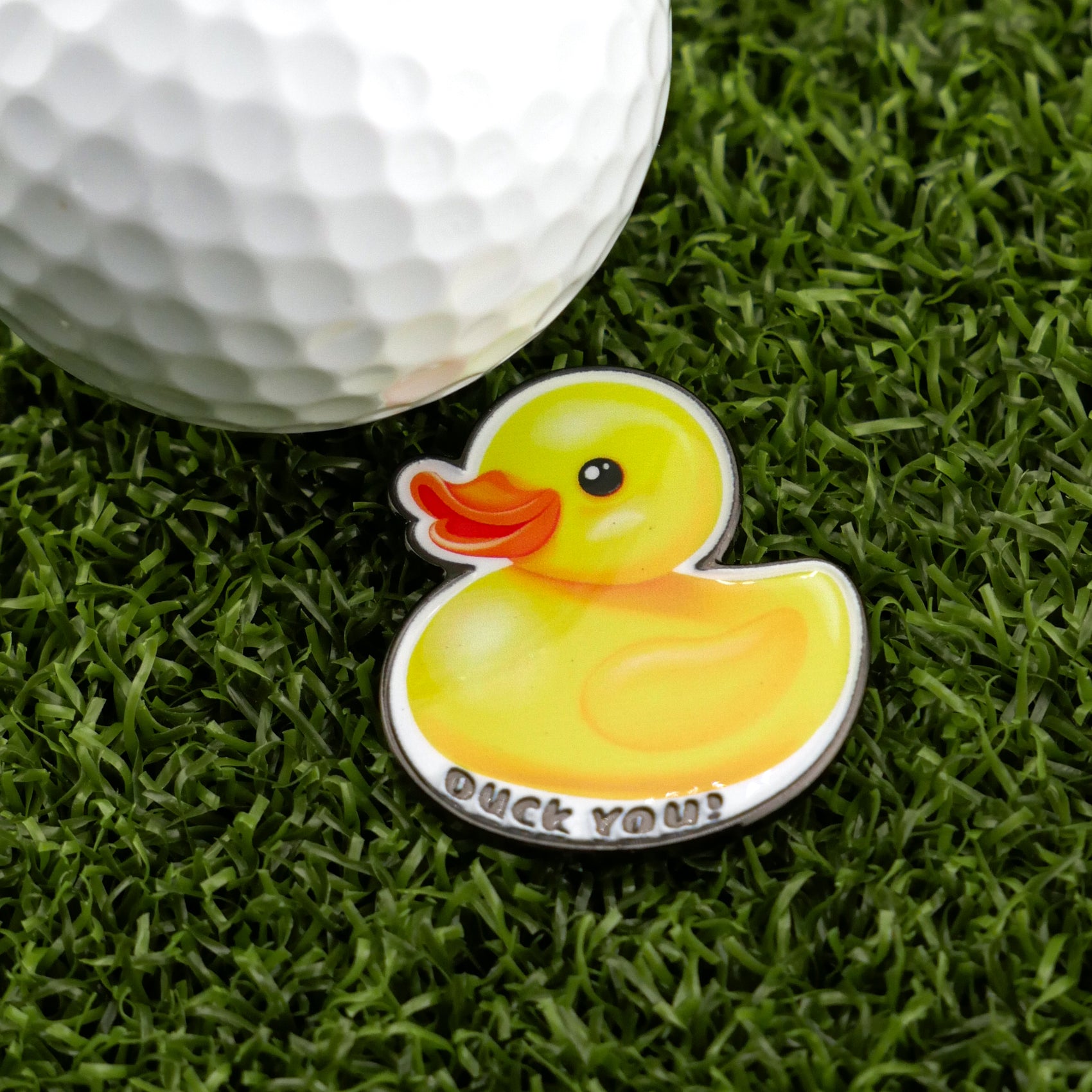 Logie Joe's Golf presents Rubber Duck You: a premium golf ball paired with a fun, duck-shaped "Duck You!" marker, both displayed on green artificial grass.