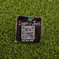 The Scan Me square sticker by Logie Joe's Golf features a QR code, “Logie Joe’s Golf” text above a pink flamingo and palm tree graphic, and “SCAN ME” below—a fun accessory for golf fans seeking premium markers.