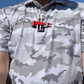 A person wears a patterned, short-sleeve shirt with THE BYRD GOLF DIVOT CLYP by The Byrd, LLC—an in-demand golf accessory with low stock—clipped to their chest, photographed from the neck down against a blue sky.