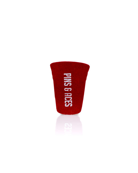 The Red Party Cup Ball Marker by Pins and Aces features "PINS & ACES" printed vertically in white on a red background—a premium golf accessory perfect for any enthusiast.