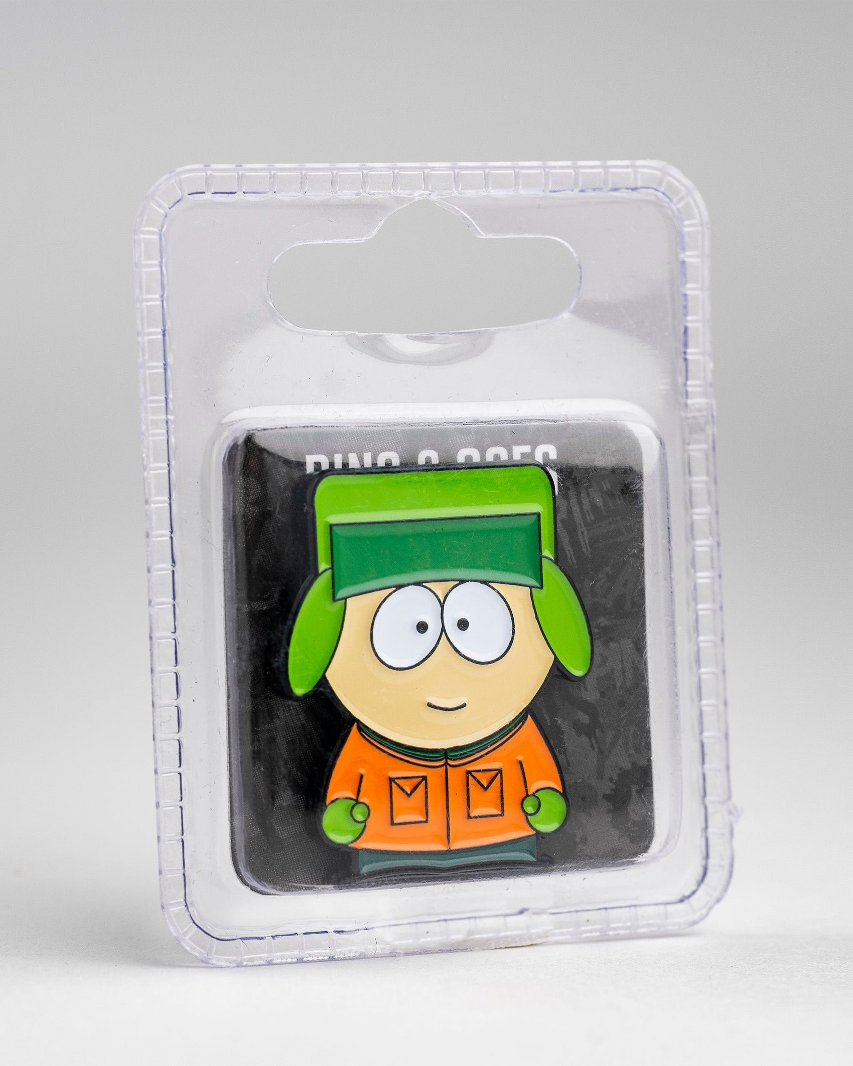 The Pins and Aces South Park Ball Marker - Kyle features a cartoon boy in a green hat and orange jacket, displayed in clear plastic packaging.