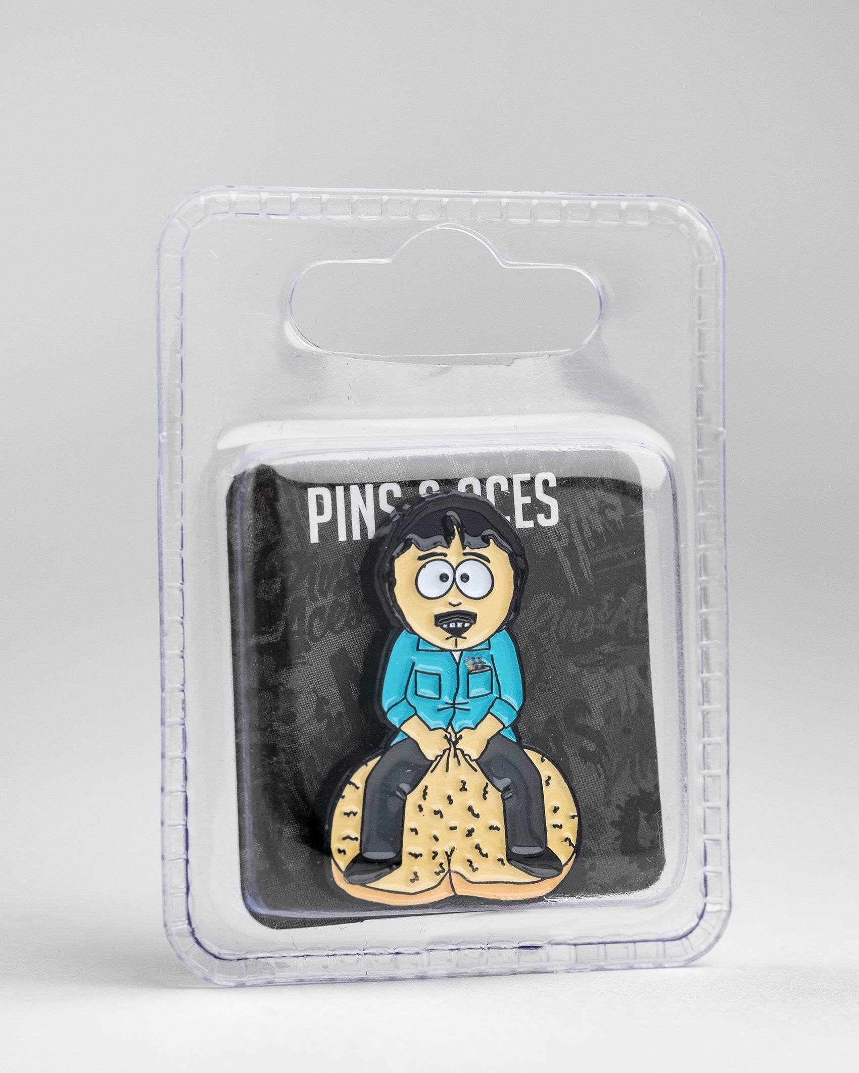 The South Park Ball Marker - Randy by Pins and Aces features a cartoon enamel pin of Randy with disheveled hair, wide eyes, and open mouth on a sand mound—perfect for any Pins and Aces or South Park golf collection.