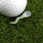 The Logie Joe's Golf Sperm Cell pin features a smiling face and cartoonish design, sitting on green turf beside a golf ball—making it a fun and unique addition to your premium golf accessories as a memorable ball marker.