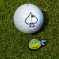 The Pins and Aces TMNT - Leonardo Ball Marker, featuring a fun cartoon design, sits next to a white golf ball with a black spade logo on green grass—perfect for Teenage Mutant Ninja Turtles golf fans.