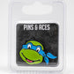 The Pins and Aces TMNT - Leonardo Ball Marker features a green cartoon turtle head with a blue mask and big smile, inspired by Leonardo, packaged in a clear case—an essential Teenage Mutant Ninja Turtles golf accessory.