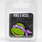 A TMNT - Donatello Ball Marker by Pins and Aces, featuring a cartoon turtle face with a purple mask, is shown on a black Pins and Aces card inside clear plastic packaging against a white background.