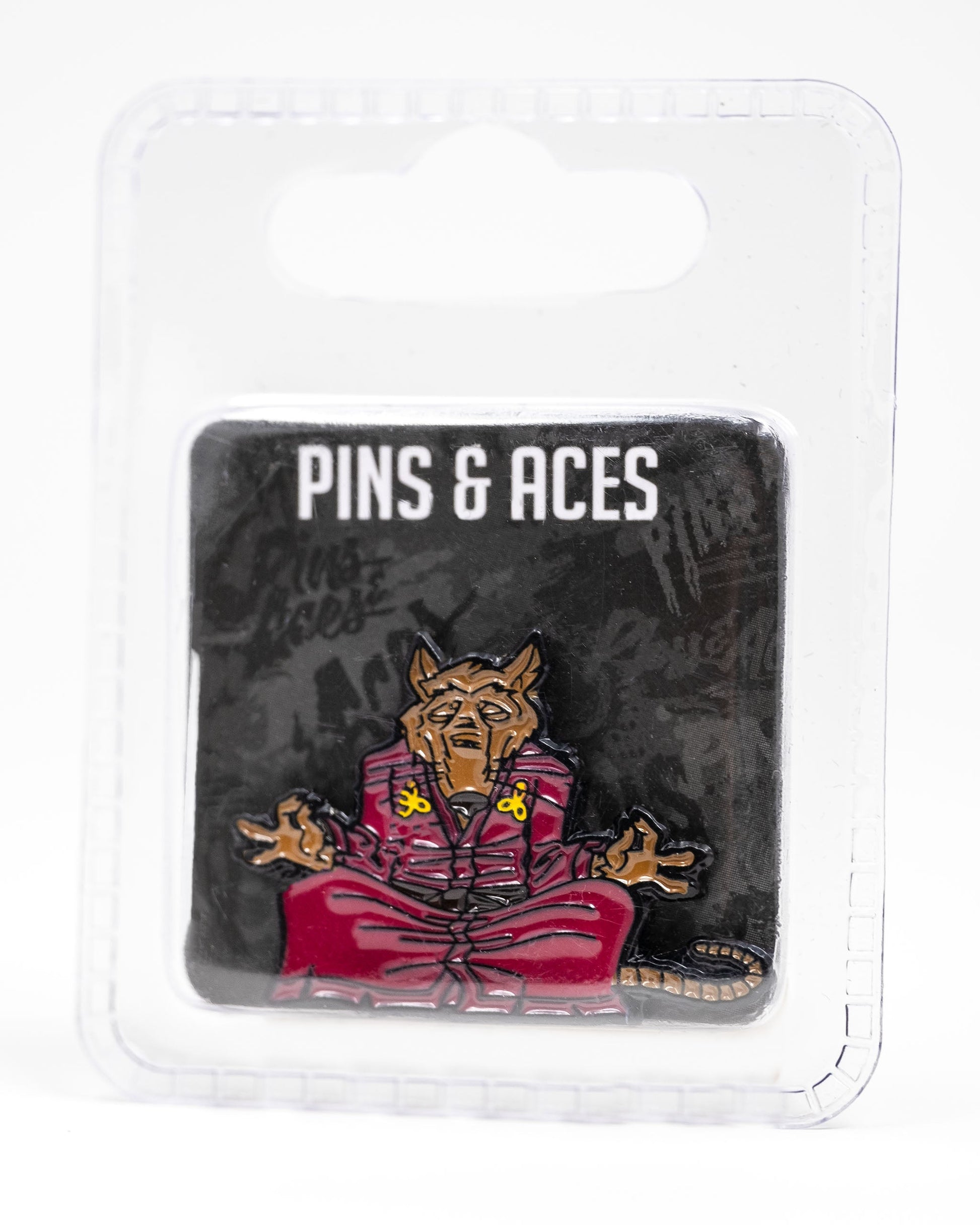 The TMNT - Splinter Ball Marker from Pins and Aces features a meditating brown rat in a red robe, inspired by Splinter. Packaged on a black card with branding in a clear case—perfect for TMNT fans and golf accessory collectors.