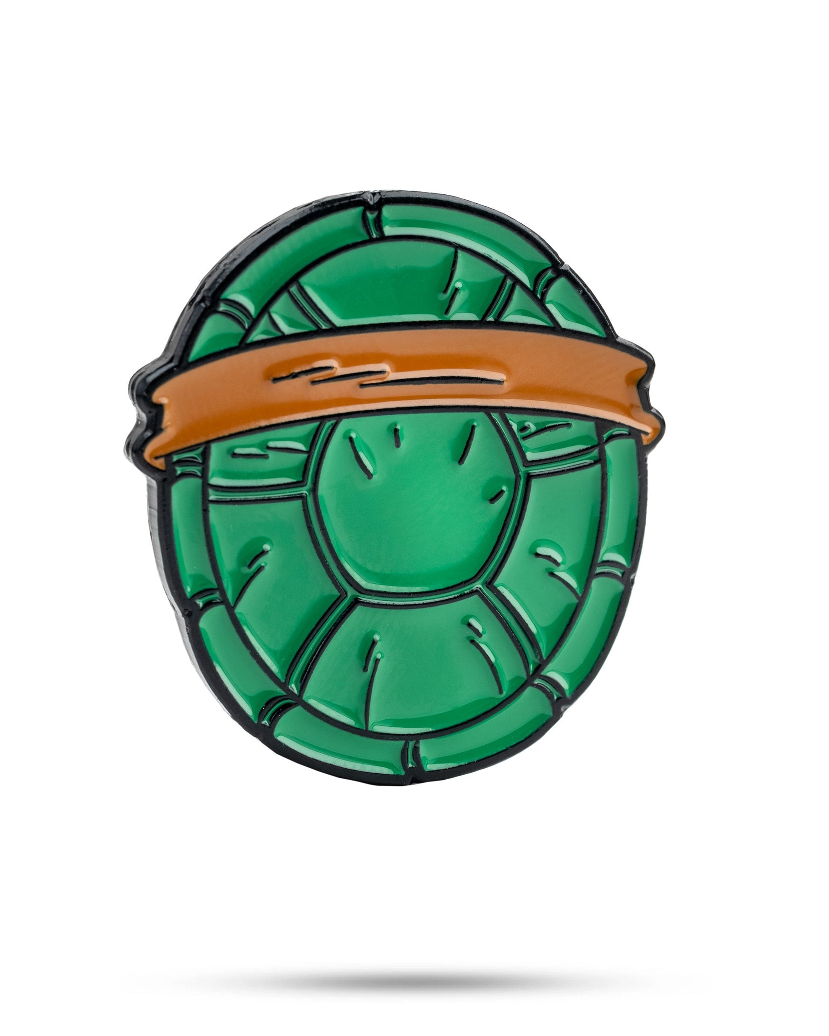 The TMNT - Shell Shock Ball Marker by Pins and Aces features a green turtle shell design with an orange top band, inspired by Teenage Mutant Ninja Turtles, and is shown on a white background with a subtle shadow.