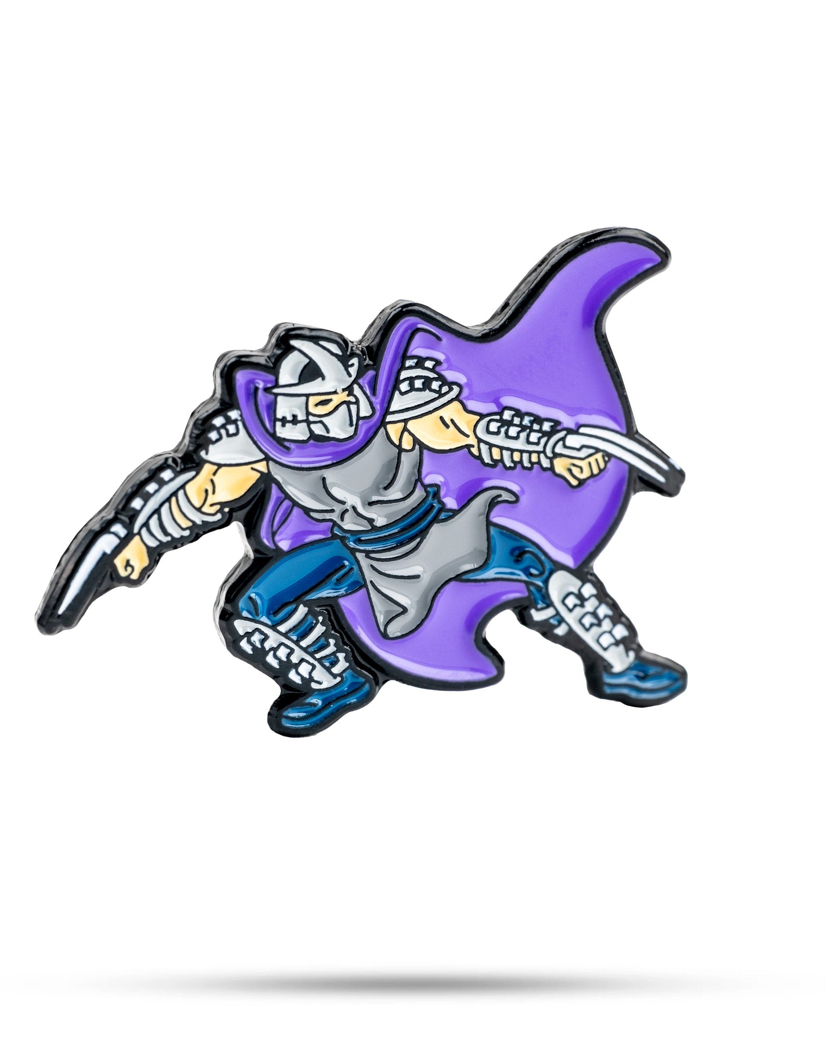 The Pins and Aces TMNT - Shredder Ball Marker is a cartoon-style enamel pin featuring a masked warrior in silver armor with a purple cape, crouched in an action pose, set against a white background.