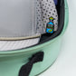 A light grey cap with a colorful tequila bottle pin is stored in a Pins and Aces Hat Caddie, featuring a mint green exterior, black zipper, and polka dot lining.