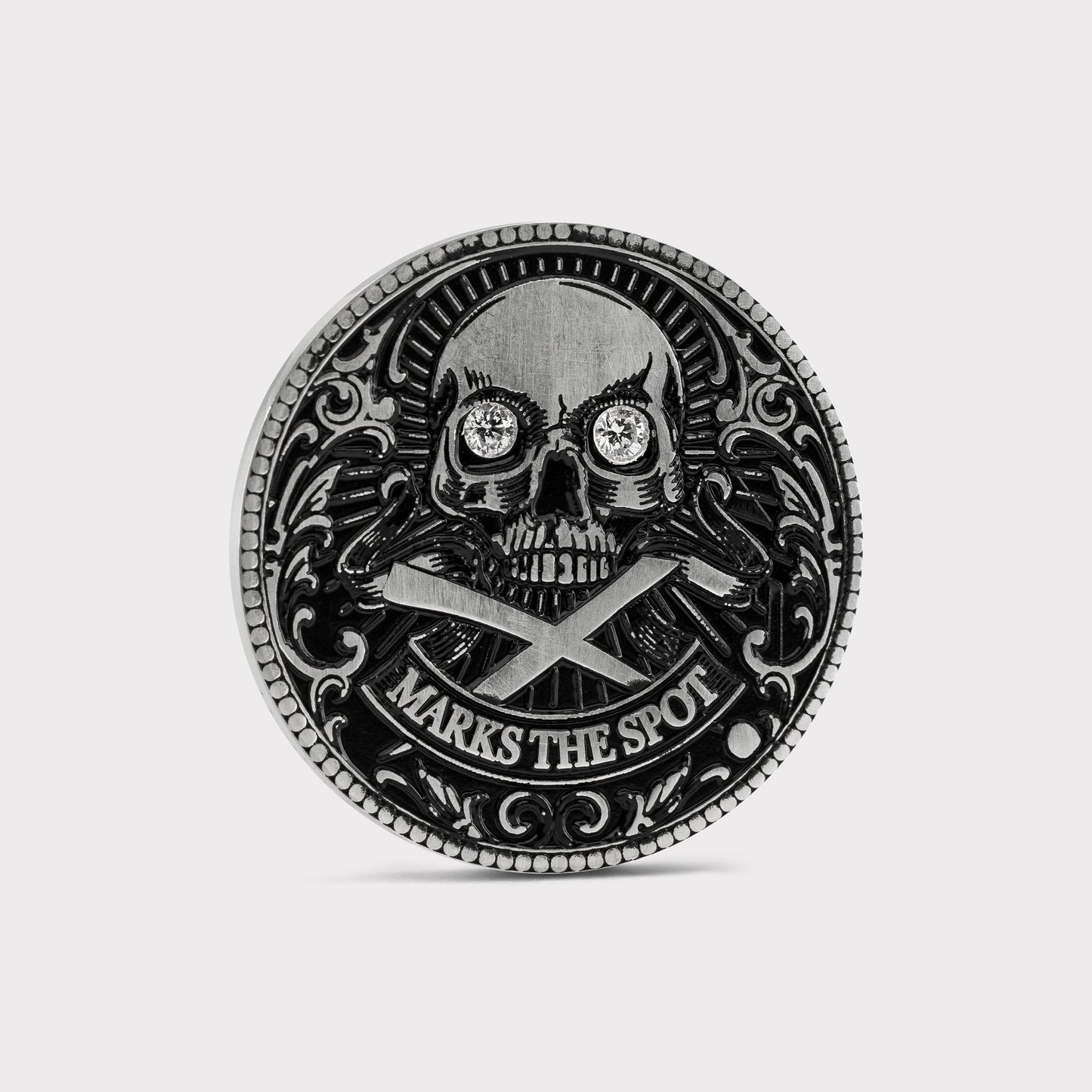 The Omen Classic Antique, Diamond & Silver Edition by Doubloon is a round, metallic golf marker with a lab-grown diamond skull, crossed bones, intricate edge detail, and “MARKS THE SPOT” engraved at the bottom.