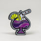 The Transfusion Spade Ball Marker by Pins and Aces is an enamel pin shaped like a spade, featuring a purple drink with a striped straw and lemon slice—ideal for golf fans or unique ball marker collectors.
