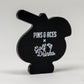 The Pins and Aces Transfusion Spade Ball Marker features a black, cartoon-inspired design with the brand's logo and "Golf Drinks" in white text—an ideal choice for fans seeking a unique golf ball marker.