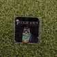 A square pin called "Trash Panda" by Logie Joe’s Golf shows a raccoon holding a colorful cup with a flamingo, set on artificial grass. The backing card features “LOGIE JOE’S” and a palm tree, perfect for premium golf accessory fans.