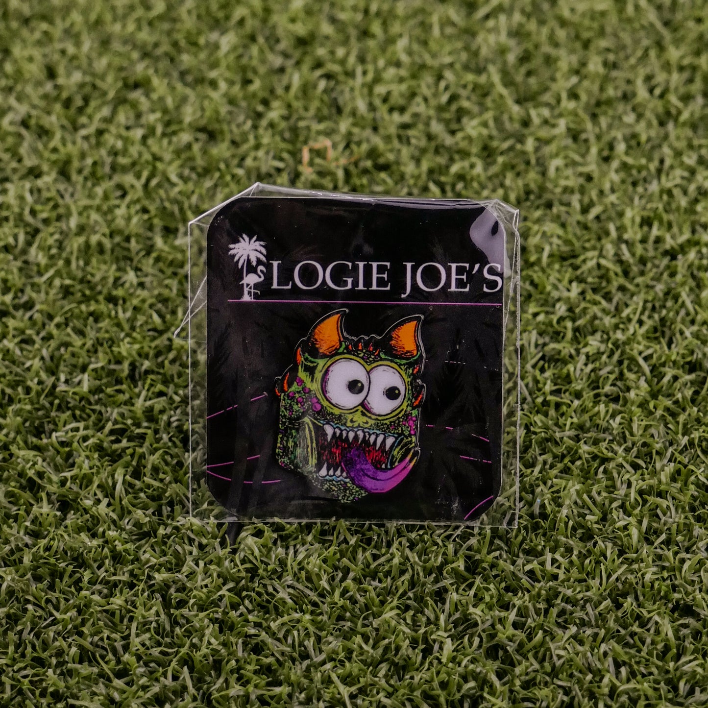 A vibrant enamel pin called Troll from Ballmarkers by Logie Joes features a funny, wide-eyed monster with horns and tongue. Attached to branded card on turf, it’s a unique ball marker for fans of premium golf accessories.