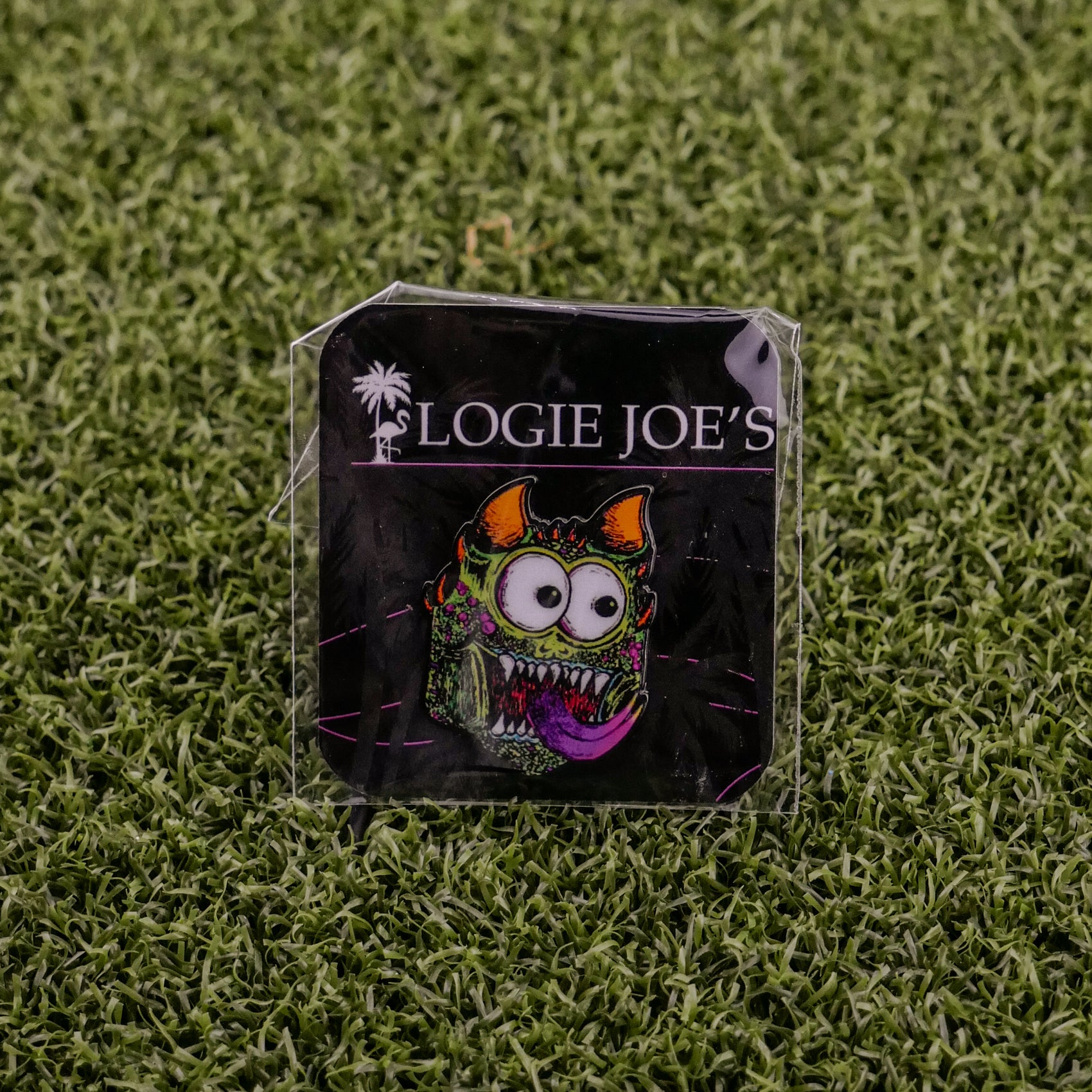 A vibrant enamel pin called Troll from Ballmarkers by Logie Joes features a funny, wide-eyed monster with horns and tongue. Attached to branded card on turf, it’s a unique ball marker for fans of premium golf accessories.