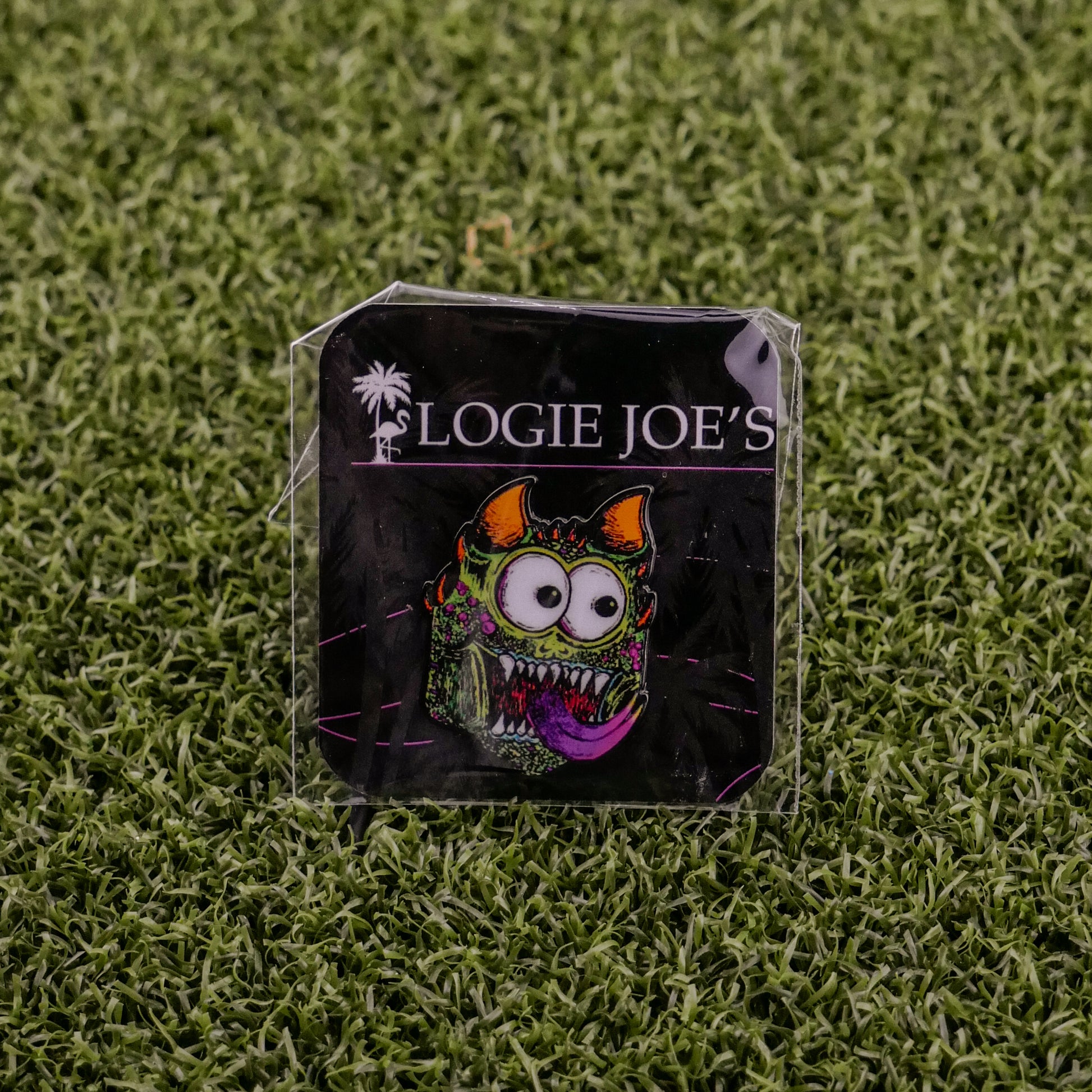 A vibrant enamel pin called Troll from Ballmarkers by Logie Joes features a funny, wide-eyed monster with horns and tongue. Attached to branded card on turf, it’s a unique ball marker for fans of premium golf accessories.
