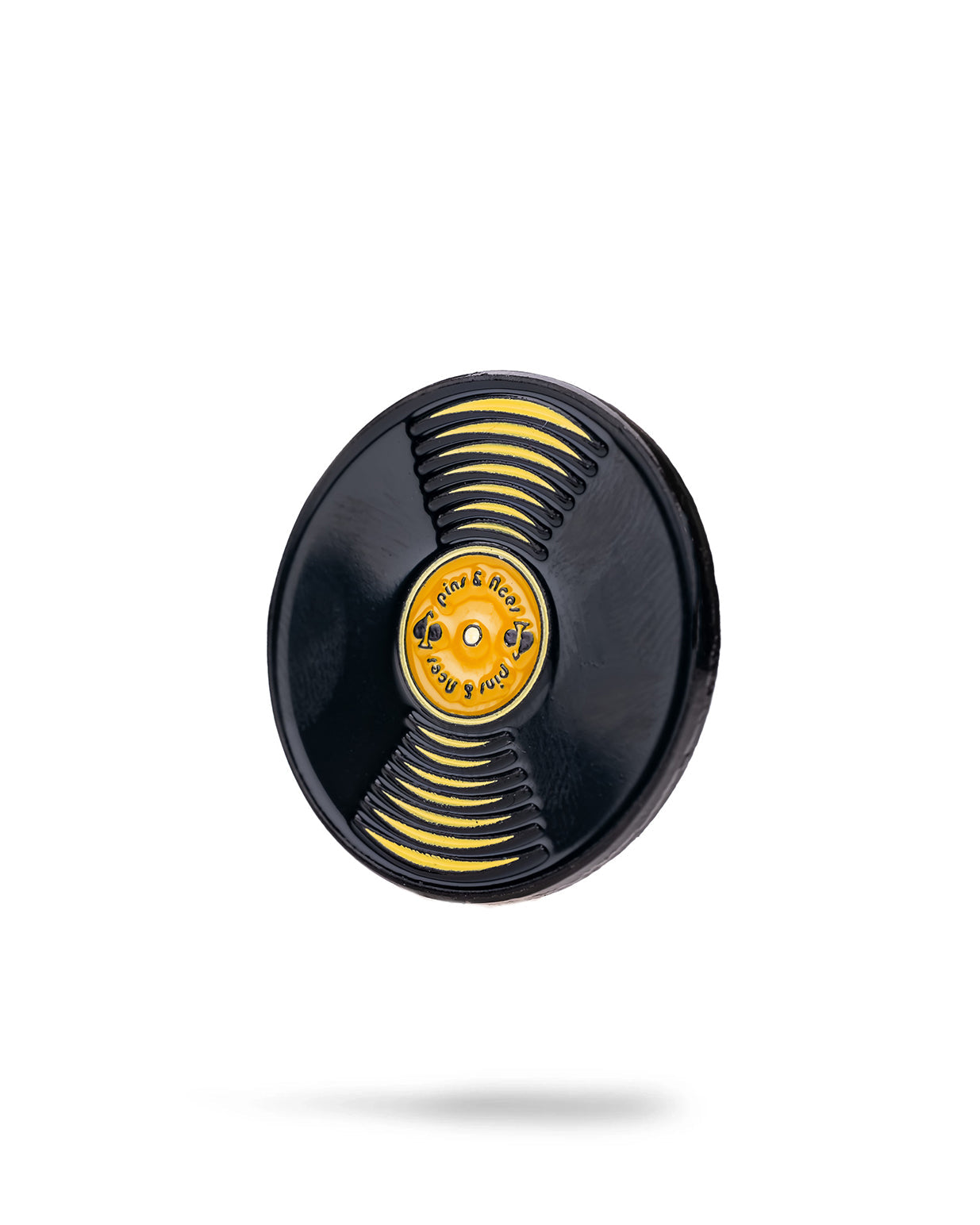 A black and yellow Vinyl Record Ball Marker by Pins and Aces, featuring "Rock & Roll" in the center, is displayed on a stainless steel magnetic surface with a subtle shadow below.