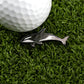 A Killer Whale-shaped golf ball marker by Logie Joe's Golf sits on green artificial grass beside a white golf ball, bringing a playful touch to your golf accessories.