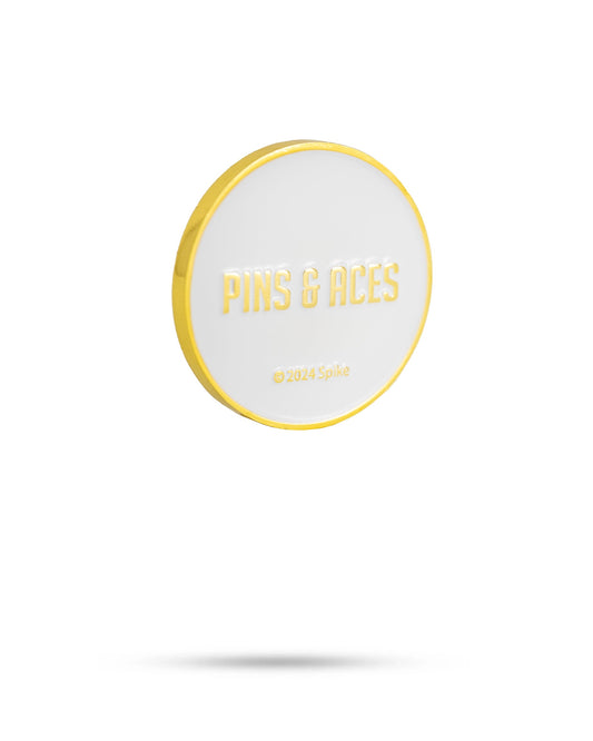 A round, white Yellowstone Ball Marker by Pins and Aces features a gold border and embossed gold text, "PINS & ACES © 2024 Spike," shown on a plain white background with a subtle shadow.