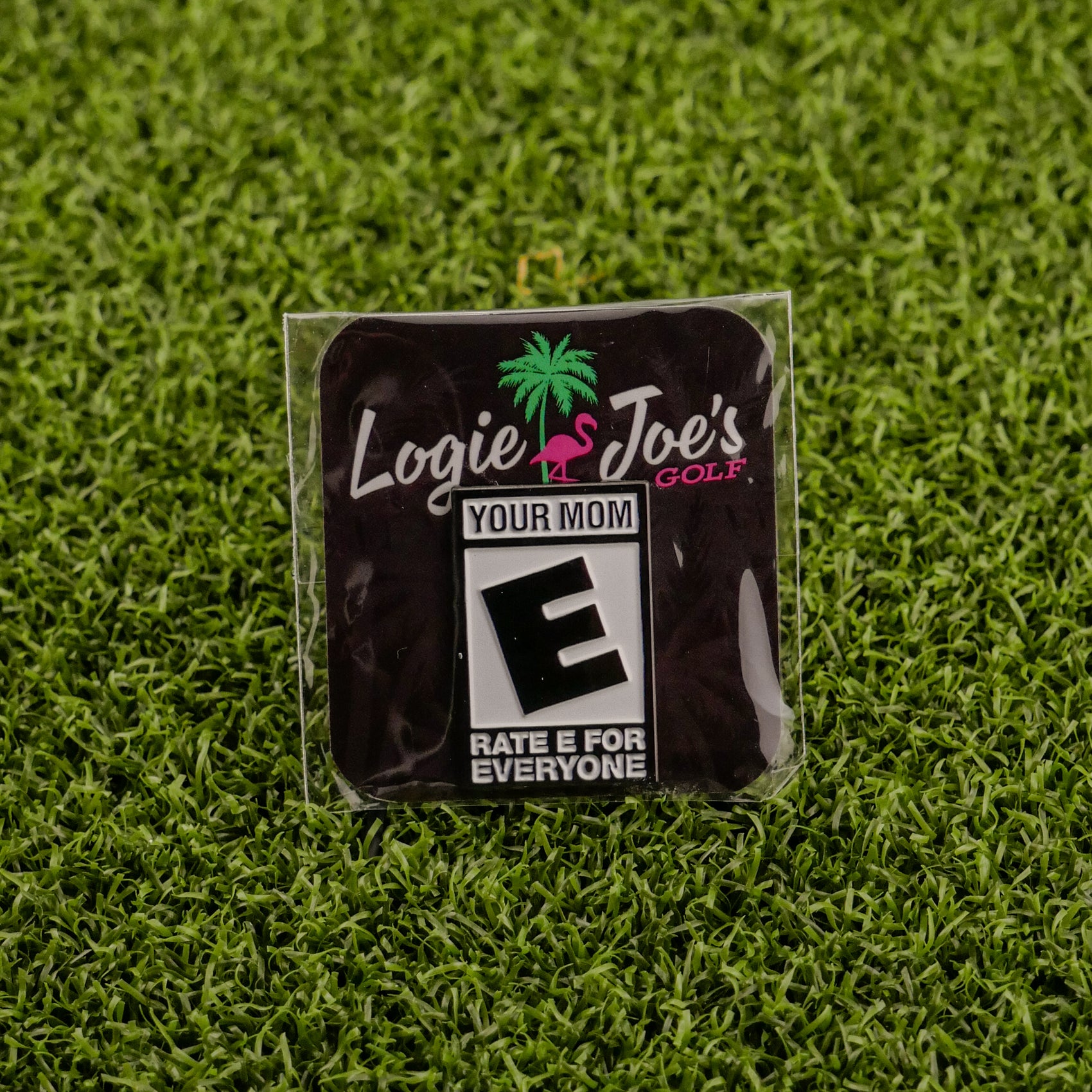 Ballmarkers by Logie Joe’s offers the “Your Mom ‘Rated E’” premium ball marker featuring a pink flamingo, palm tree, and vibrant text—ideal for golf lovers seeking unique and funny accessories.
