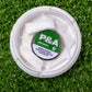 An open 6 Milly - Spearmint Ball Marker by Pins and Aces, with white rectangular pouches inside, rests on artificial green grass next to a magnetic ball marker. The product warning text appears on the lid.