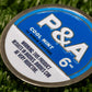 A round blue and silver tin labeled "6 Milly - Cool Mint Ball Marker" by Pins and Aces rests on artificial grass, its magnetic lid perfect for ball markers. Warning: This product results in birdies. Birdies can be very addictive.