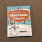 A box labeled The Ultimate Golfers Ballmarkers Advent Calendar by Custom, decorated with snowman and golf-themed winter illustrations, is placed on a brown carpet.