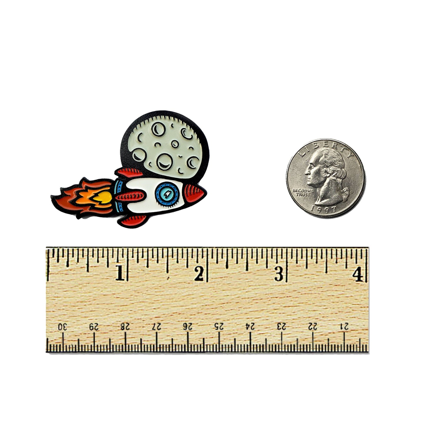 The Kolorspun Rocket Ship Golf Ball Marker is a small enamel pin featuring a rocket and moon, shown next to a U.S. quarter and ruler for scale. Measuring about 1.5 inches, it makes a unique golf gift or custom ball marker.
