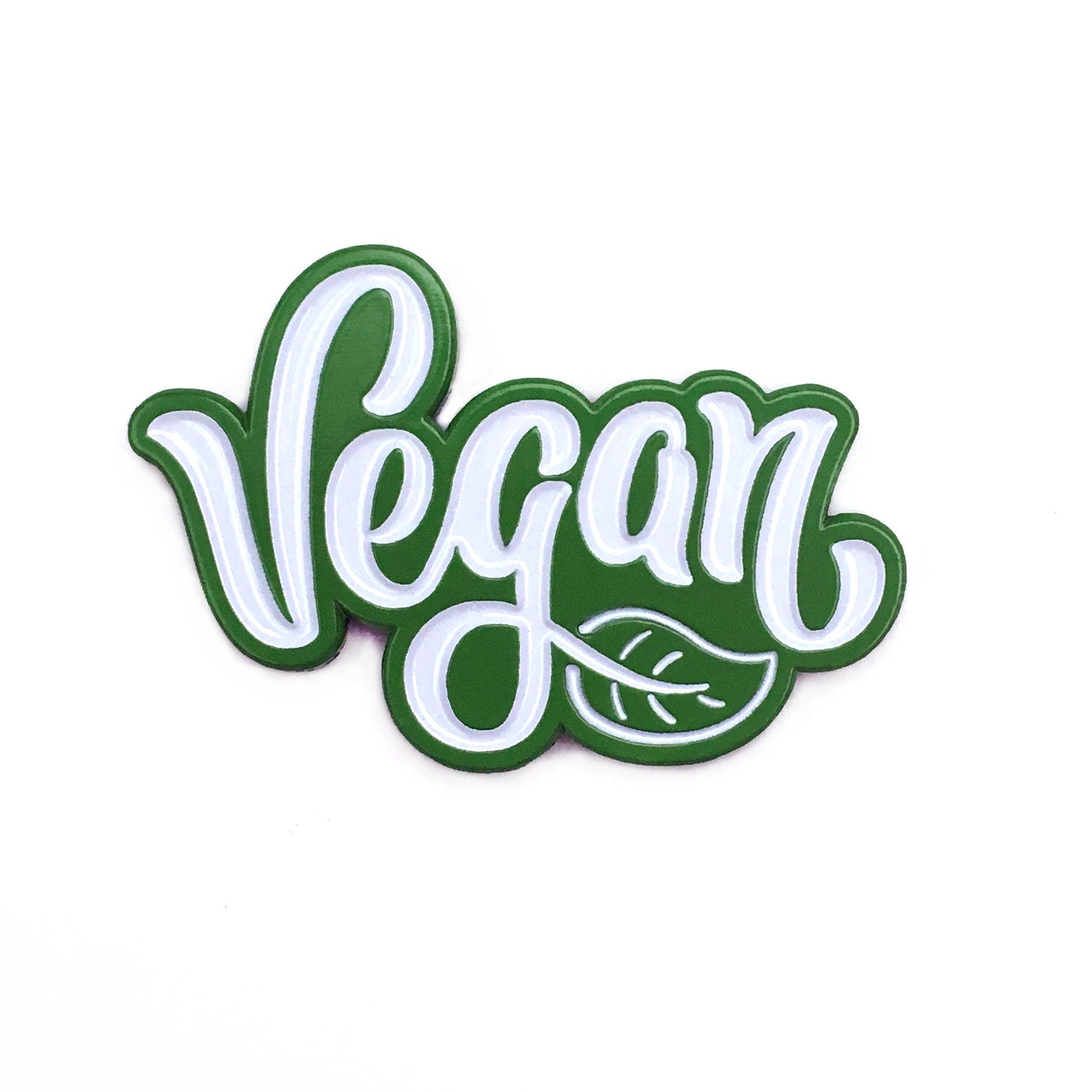 The Kolorspun Vegan Golf Ball Marker is a green and white magnetic marker with "Vegan" in cursive and a leaf design—ideal as a custom golf gift or unique accessory for golfers.