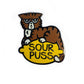The Kolorspun Sourpuss Cat Golf Ball Marker features a grumpy brown cartoon cat on a yellow lemon labeled "SOUR PUSS" atop a white background—perfect as a quirky, custom golf gift.
