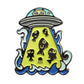 The Kolorspun Glowing UFO Cat Golf Ball Marker features a cartoon UFO with a cat beaming up six fish in green light, surrounded by blue and white clouds—an ideal whimsical golf gift.