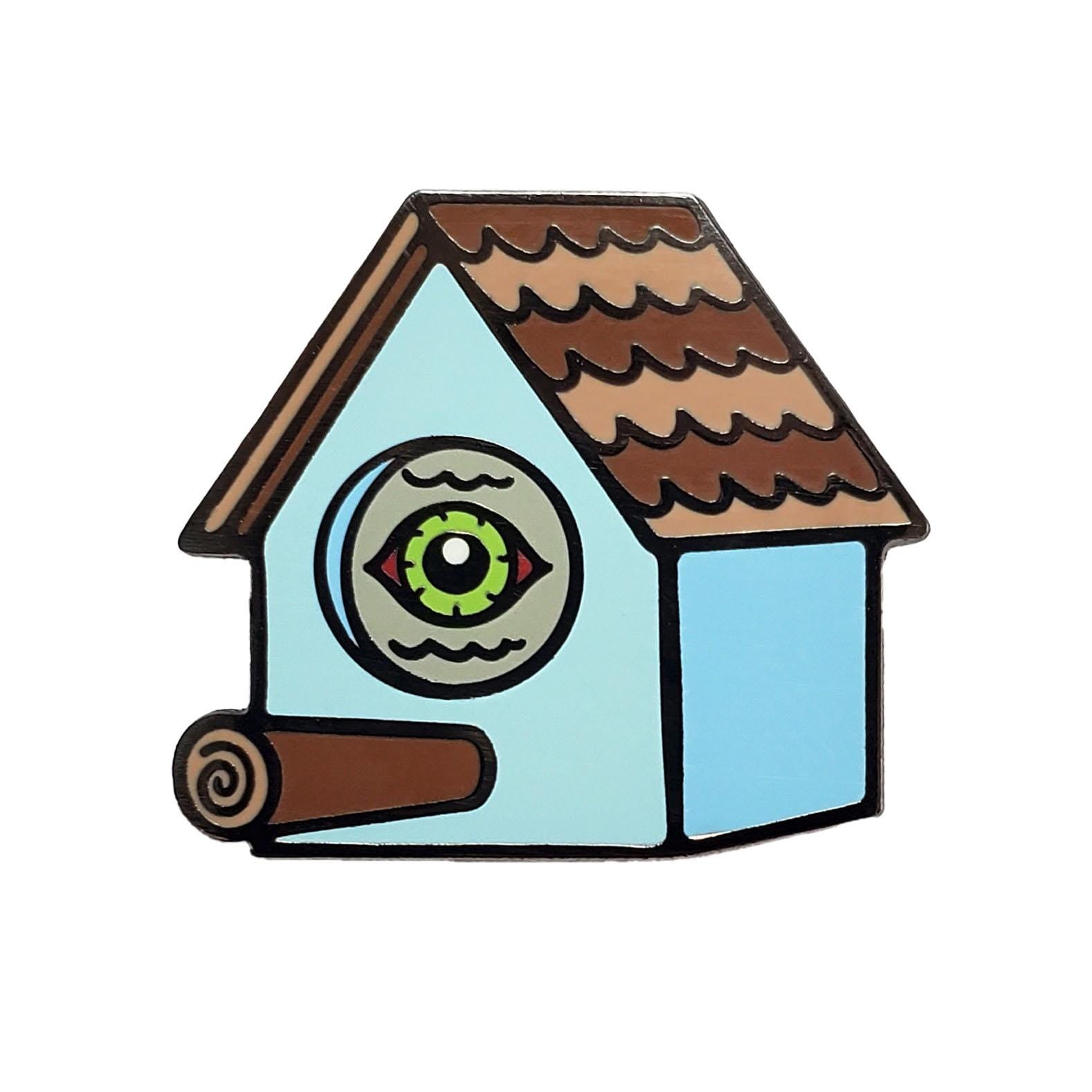 Kolorspun’s Bird Watching Birdhouse Golf Ball Marker features a cartoon birdhouse with a brown roof, blue walls, a large rolled-up cigar as the perch, and a custom golf ball marker for the green eye where the entrance hole would be.