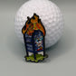 A golf ball sits behind the "UPS Dumpster Fire" enamel pin by Crown Golf Designs, showing a blue mailbox with graffiti and cartoon flames, and featuring a magnetic backing for easy display.