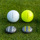 Two OnPointGolf.us Two Rail Ball Markers, one for a white ball and one for a yellow ball, sit on grass, each matching the alignment lines of its golf ball—creating a practical alignment tool and putting aid.