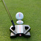 A close-up of the OnPointGolf.us Three Rail Ball Marker and a putter lined up with a golf ball on the green, both displaying red and blue alignment lines to help aim your shot.