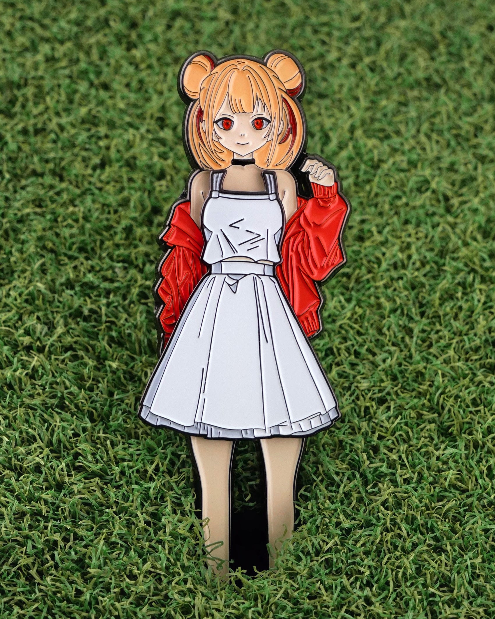The Japanese Anime enamel pin from Ballmarkers.com showcases an anime-style girl with orange hair and a red jacket, standing on grass—perfect as a unique golf ball marker.
