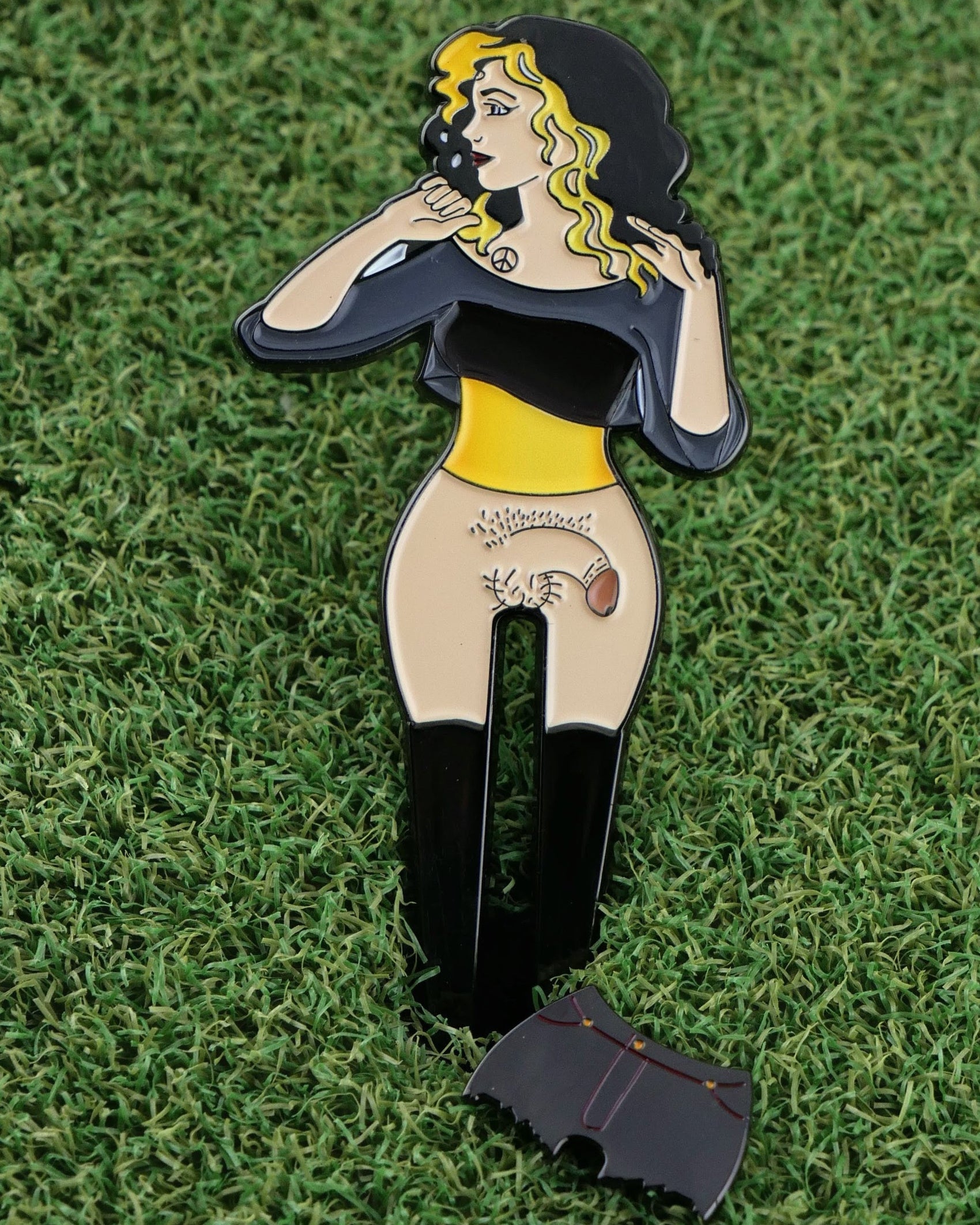Lady Boy 2.0 by Ballmarkers from Logie Joes is a cartoon pin of a woman with blonde and black hair, black top, and yellow belt. Her dropped skirt reveals a hedgehog—an amusing golf ball marker for those who enjoy quirky accessories.