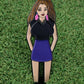 The Trifecta Chick enamel pin by Ballmarkers.com features a woman with long brown hair in a black top and purple skirt on green grass—a unique, funny golf gift that doubles as a golf accessory or ball marker.
