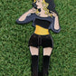 Lady Boy 2.0 by Ballmarkers.com is a cartoon-style enamel pin featuring a woman with black and yellow hair, chic outfit, and boots—displayed on green turf, it's the perfect golf accessory for stylish fans.